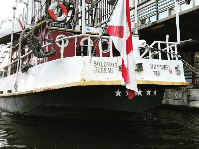 a red and white boat sitting next to a body of water
